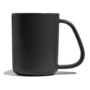 May include: A black ceramic mug with a rounded handle. The mug is smooth and has a matte finish.