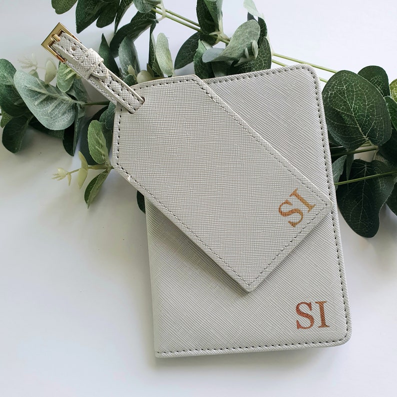 May include: A gray leather passport holder and luggage tag set with gold accents and the initials "SI" embossed in gold.