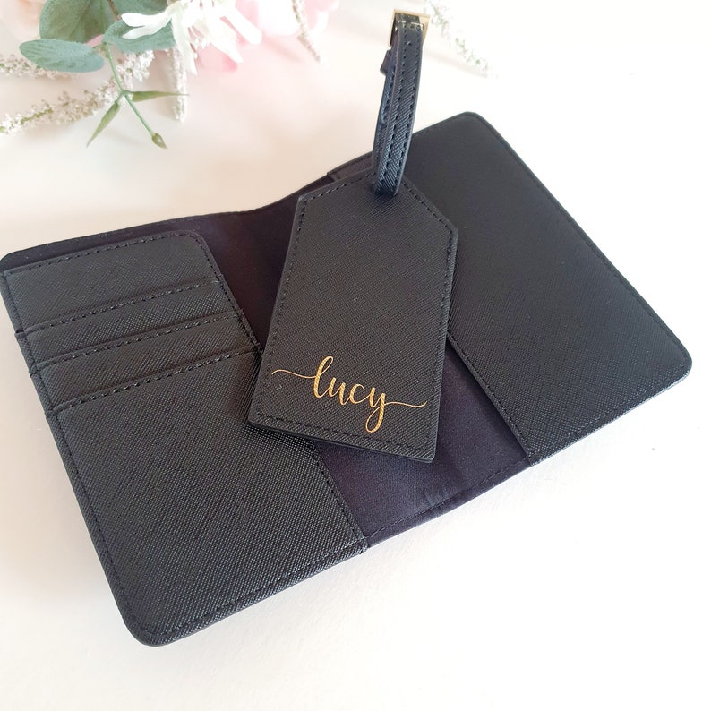 May include: Black passport holder with a matching luggage tag. The tag has the name "Lucy" written in gold script.