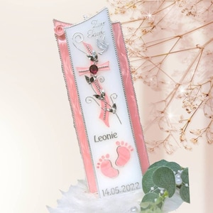 Könnte beinhalten: Rosa-weißer Glas-Kerzenhalter mit einem silbernen Kreuz, einer Taube und einem rosa Band. Der Kerzenhalter trägt den Namen "Leonie" und das Datum "14.05.2022" eingraviert.