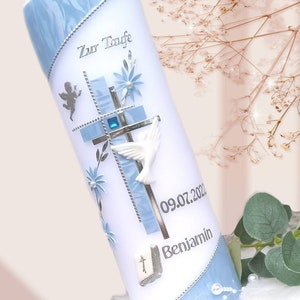 Könnte beinhalten: Weiße Taufkerze mit blauen Akzenten, verziert mit Kreuz, Taube und floralen Designs. Die Kerze trägt den Text "Zur Taufe" und den Namen "Benjamin" mit dem Datum 09.07.2022.