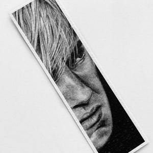 Puede incluir: Dibujo a l&aacute;piz en blanco y negro del rostro de una persona en un marcap&aacute;ginas. El retrato presenta una representaci&oacute;n detallada de la nariz, la boca y el cabello de la persona. El marcap&aacute;ginas es rectangular con borde blanco.