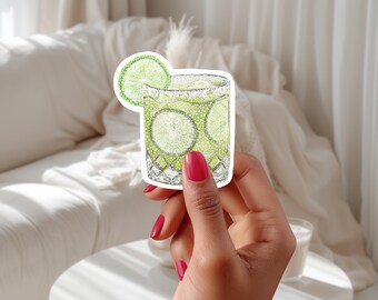 May include: A sticker of a green cocktail with a lime wedge, drawn in a sparkly style.