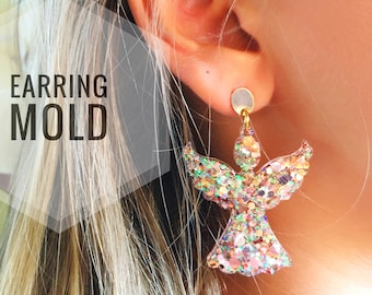 Op de afbeelding: Een paar gouden glitter engel oorbellen. De oorbellen zijn gemaakt van helder hars en zijn gevuld met iriserende glitter. De oorbellen hangen aan een gouden haak.