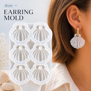 May include: A white silicone earring mould with six seashell-shaped cavities. The text "25 mm" and "EARRING MOLD" are visible. A finished iridescent seashell earring is shown, hanging from a gold hoop earring.