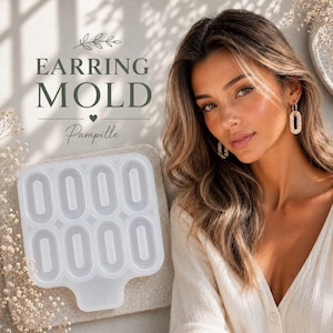 Pode incluir: Um molde de brinco transparente em forma oval com oito cavidades. O texto "EARRING MOLD" e "Pampille" está impresso na imagem. O molde está sobre uma superfície de cor neutra.