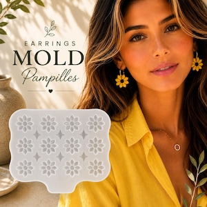 Peut inclure: Un moule en silicone translucide pour la création de boucles d'oreilles, présentant une forme rectangulaire avec douze cavités en forme de fleurs répétées et de petits accents en forme de losange. Le texte EARRINGS MOLD Pampilles est imprimé au-dessus.