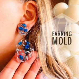K&ouml;nnte beinhalten: Ein Paar transparente Harzohrringe mit gepressten blauen Blumen und silbernen Flocken. Die Ohrringe sind tropfenf&ouml;rmig und rund. Der Text "EARRING MOLD" ist im Bild sichtbar.