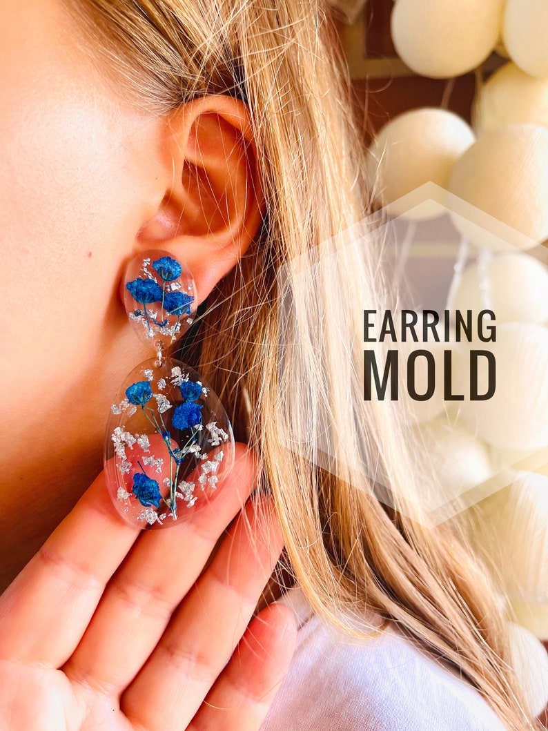 K&ouml;nnte beinhalten: Ein Paar transparente Harzohrringe mit gepressten blauen Blumen und silbernen Flocken. Die Ohrringe sind tropfenf&ouml;rmig und rund. Der Text "EARRING MOLD" ist im Bild sichtbar.
