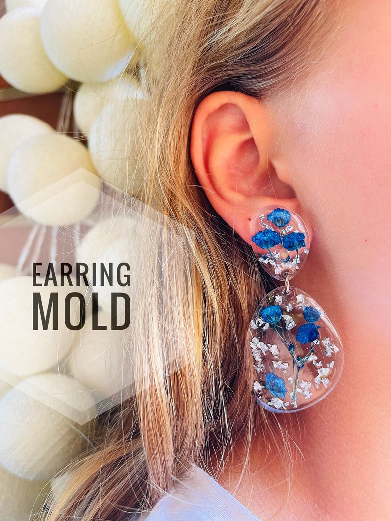 K&ouml;nnte beinhalten: Ein Paar transparente Harzohrringe mit gepressten blauen Blumen und silbernem Glitzer. Die Ohrringe sind tropfenf&ouml;rmig und rund. "EARRING MOLD" steht in wei&szlig;er Schrift auf wei&szlig;em Hintergrund.