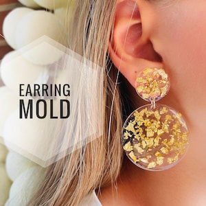May include: Clear resin earrings with gold flakes embedded inside. The earrings are round and dangle from the earlobe. The text "EARRING MOLD" is visible in the image.