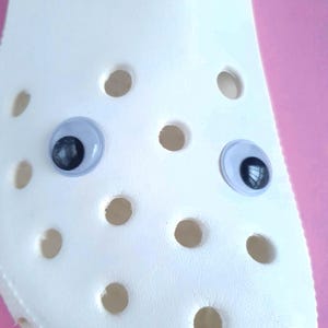 May include: White plastic shoe with two black and white googly eyes attached.