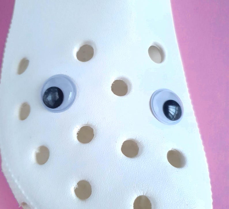 May include: White plastic shoe with two black and white googly eyes attached.
