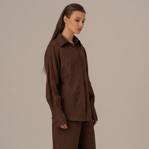 May include: A brown linen shirt and matching wide-leg trousers. The shirt has a collared neckline and long sleeves. The trousers have a straight leg and a cropped length.
