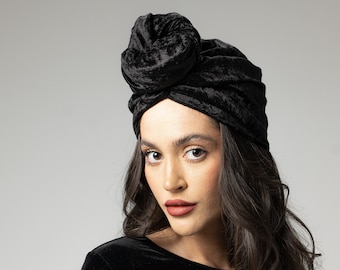 May include: A woman wearing a black velvet turban and a black velvet long-sleeved shirt.