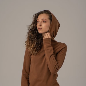 May include: A brown long-sleeved shirt with a hood. The shirt has a turtleneck collar and is made of a soft, comfortable fabric.