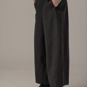 May include: A pair of dark gray wide-leg pants with a straight leg and a high waist. The pants are made of a soft, textured fabric and have a subtle sheen. The pants are paired with black platform boots.