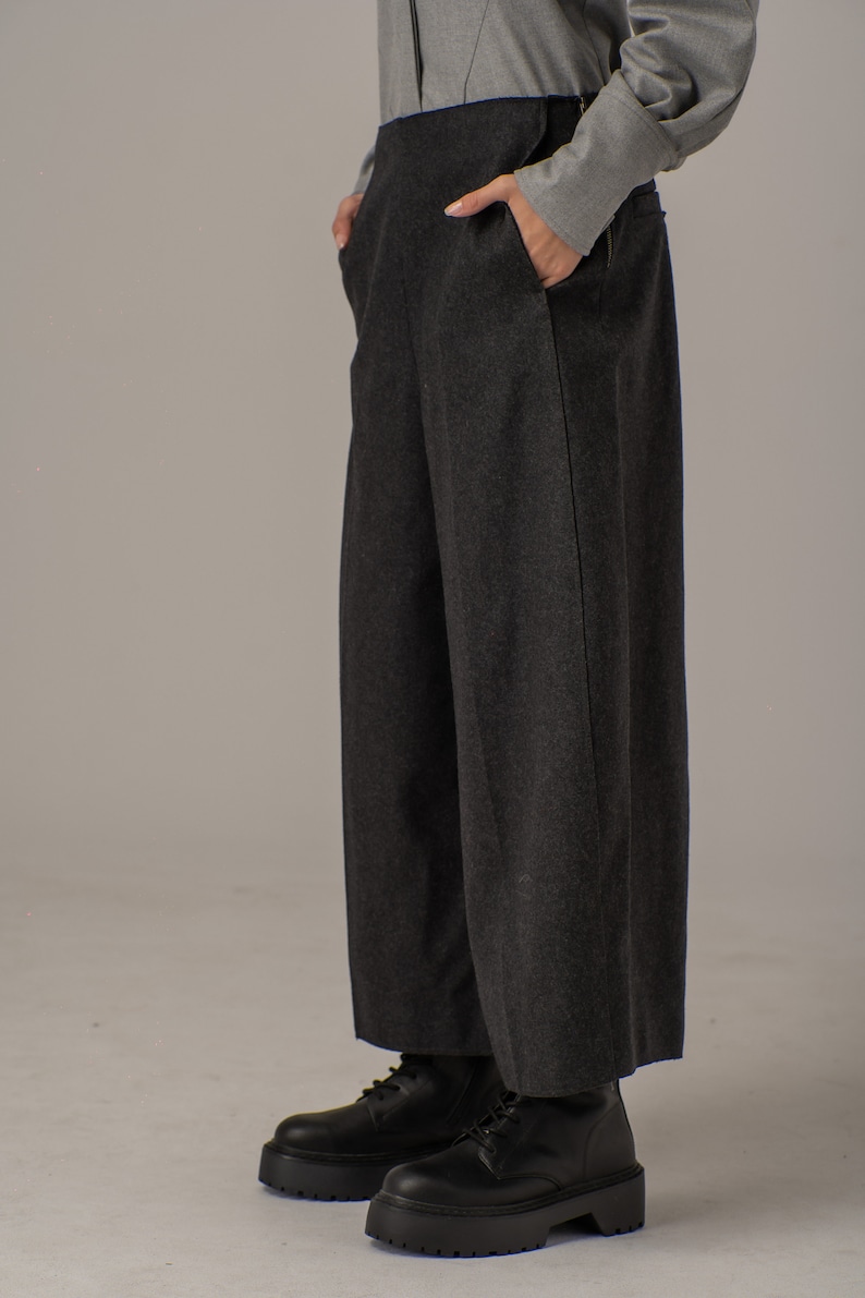 May include: A pair of dark gray wide-leg pants with a straight leg and a high waist. The pants are made of a soft, textured fabric and have a subtle sheen. The pants are paired with black platform boots.
