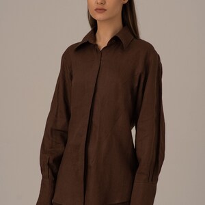 May include: A brown linen shirt and trousers set with a collared shirt and long sleeves. The shirt has a button-up front and a slightly fitted silhouette.