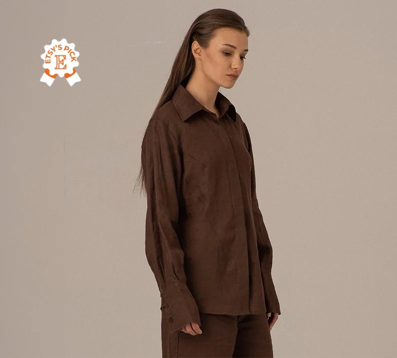 May include: A brown linen shirt with long sleeves and a button-up front. The shirt has a relaxed fit and a slightly oversized look.