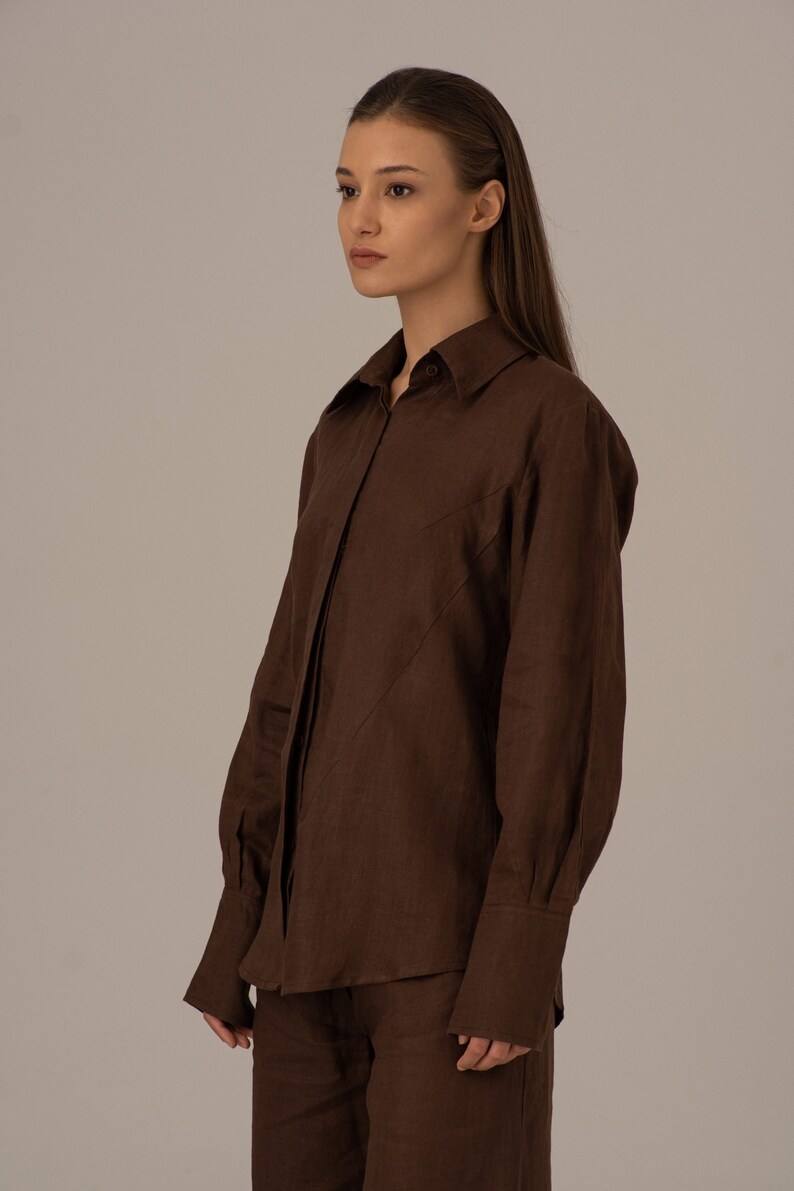 May include: A brown linen shirt with long sleeves and a button-up front. The shirt has a relaxed fit and a slightly oversized silhouette.