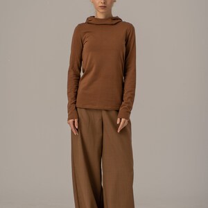 May include: A brown long-sleeved shirt with a mock neck and a pair of wide-leg brown pants.