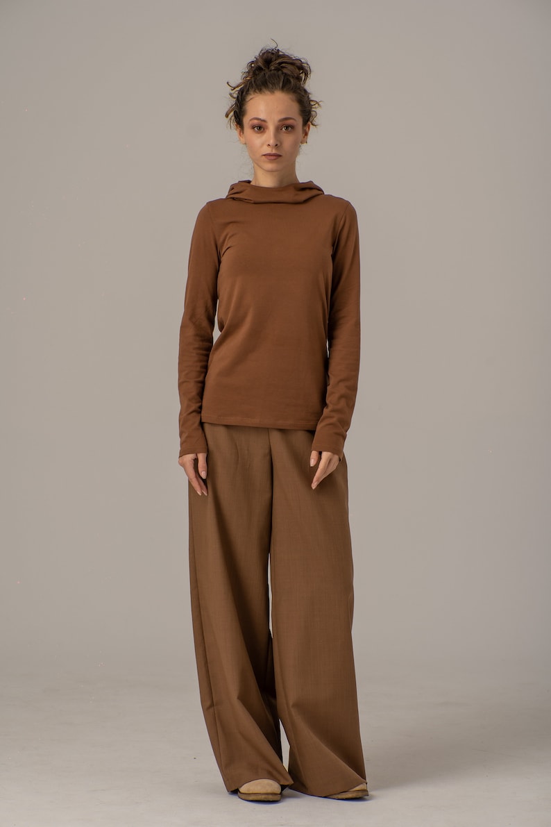 May include: A brown long-sleeved shirt with a mock neck and a pair of wide-leg brown pants.