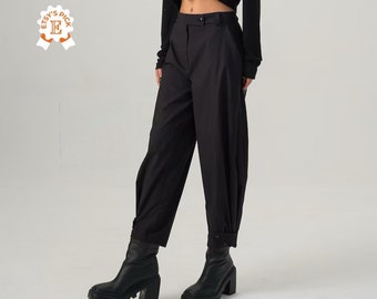 Op de afbeelding: Zwarte wijde broek met een hoge taille en gezoomde zoom. De broek is gemaakt van een gladde, lichte stof. Het model draagt ​​zwarte enkellaarsjes.