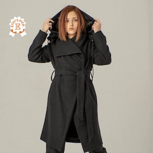 Peut inclure: Un manteau noir à capuche enveloppant avec une ceinture. Le manteau a une coupe longue et fluide et une sensation douce et luxueuse.