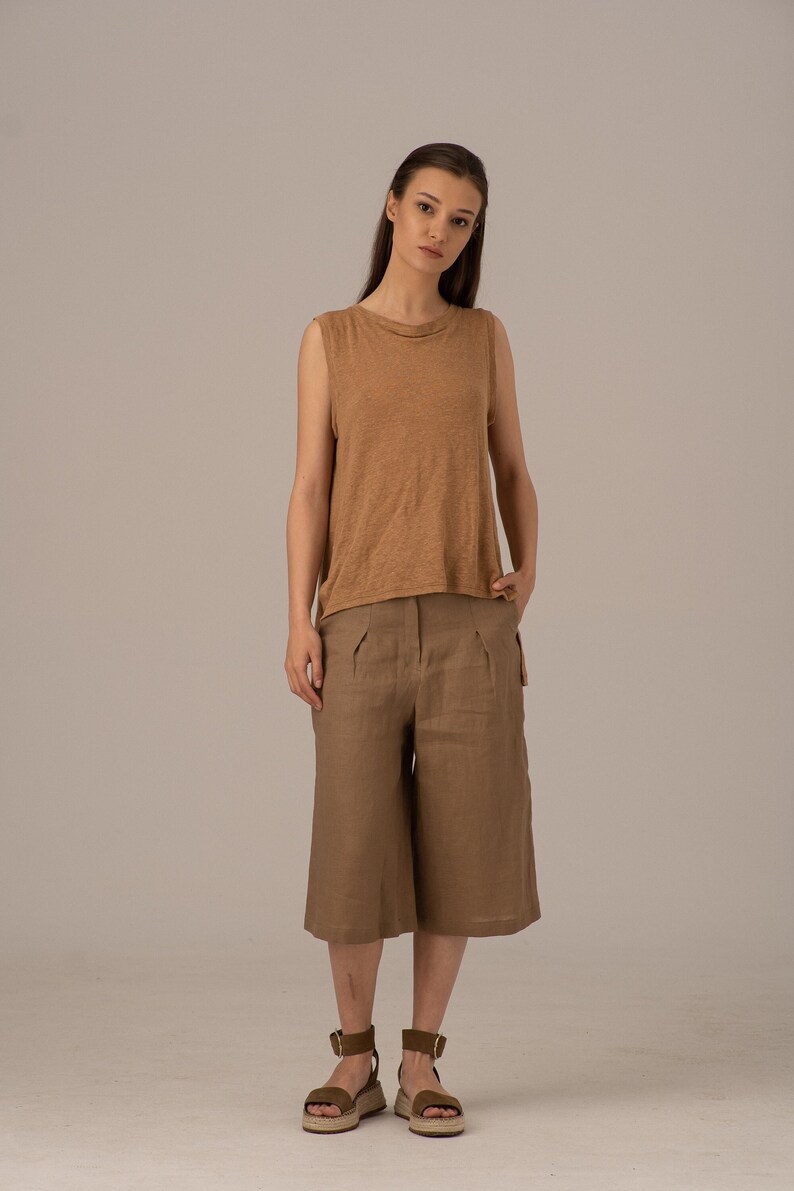 K&ouml;nnte beinhalten: Eine Frau tr&auml;gt ein braunes &auml;rmelloses Oberteil und braune Leinen-Culottes. Sie tr&auml;gt braune Sandalen mit Kn&ouml;chelriemen.