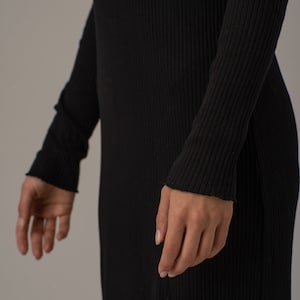 Puede incluir: Un vestido negro de manga larga de punto de canal&eacute; con silueta ajustada.