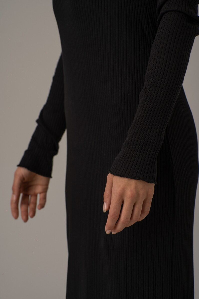 Puede incluir: Un vestido negro de manga larga de punto de canal&eacute; con silueta ajustada.