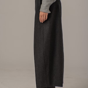 May include: A pair of black wide-leg pants with a straight leg and a slightly cropped length. The pants are made of a thick, textured fabric and have a subtle sheen.