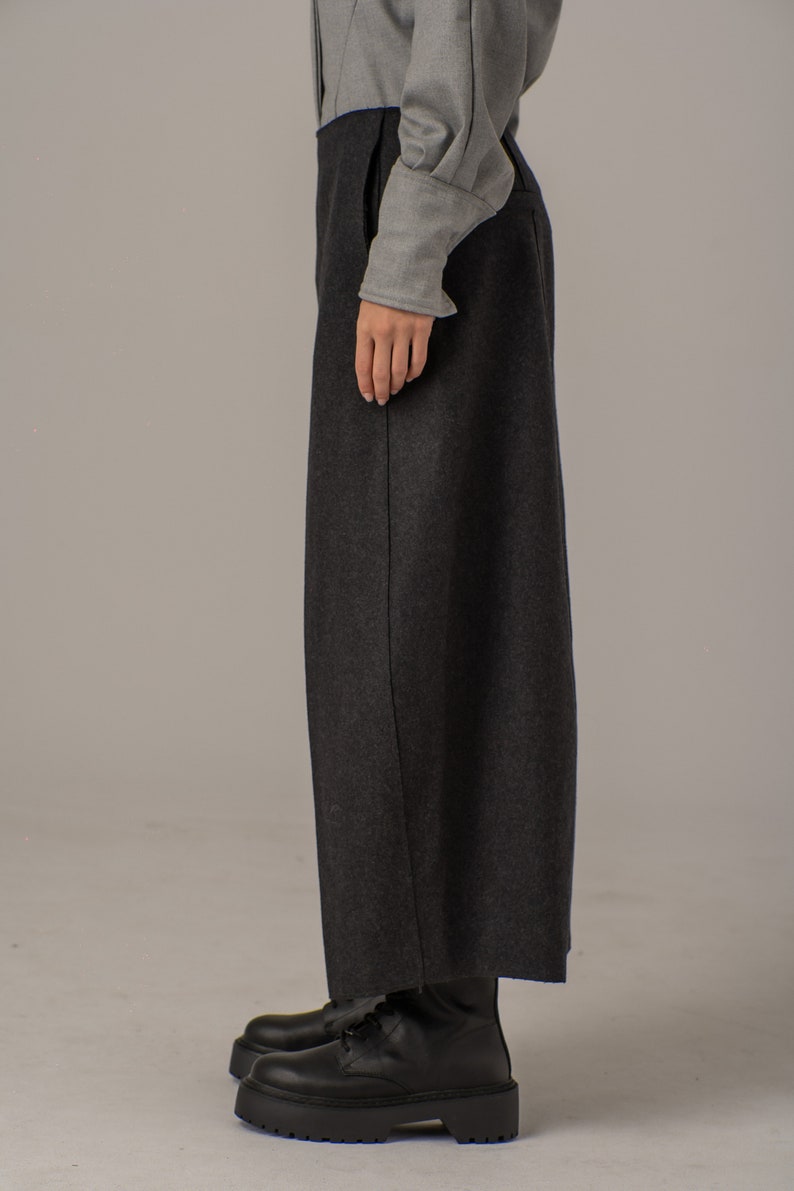 May include: A pair of black wide-leg pants with a straight leg and a slightly cropped length. The pants are made of a thick, textured fabric and have a subtle sheen.