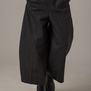 May include: Black wide-leg pants with a high waist and a relaxed fit. The pants are made of a thick, textured fabric.