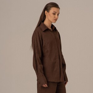 May include: A brown long-sleeved collared shirt with a button-up front.