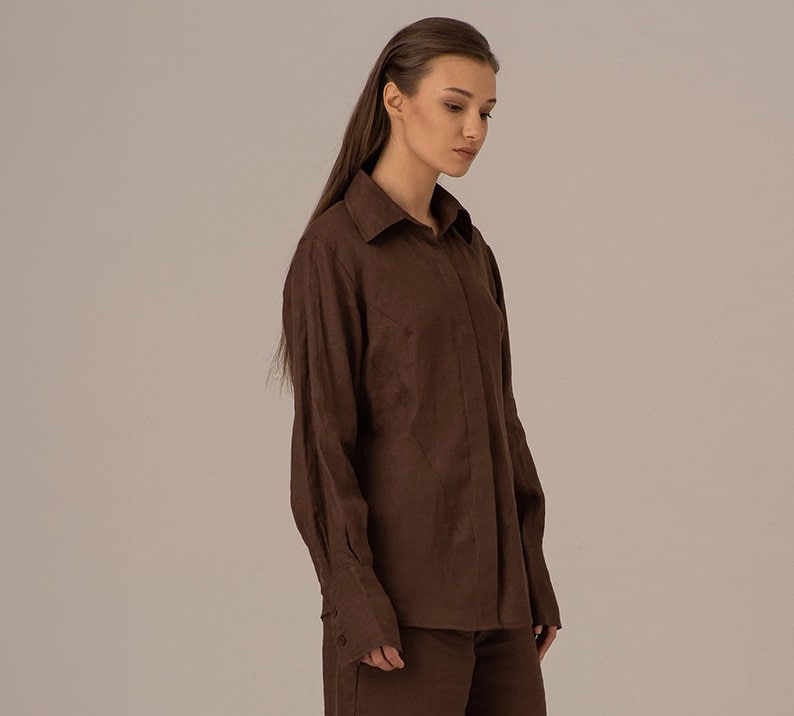 May include: A brown long-sleeved collared shirt with a button-up front.