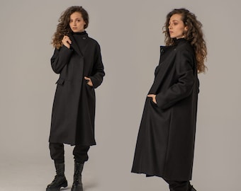 May include: Two women wearing long black coats with a single button closure. The coats have a relaxed fit and are made of a soft, comfortable fabric.