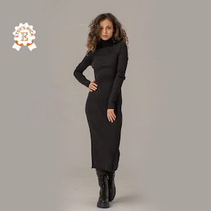 Puede incluir: Un vestido midi negro de manga larga con cuello alto. El vestido est&aacute; hecho de tejido de canal&eacute; y tiene una silueta ajustada. La modelo lleva botas negras.