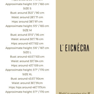 Op de afbeelding: Maattabel voor kleding met borst-, taille-, heup- en geschatte hoogtemetingen in inches en centimeters. De tabel bevat de maten XS, S, M, L, XL en XXL. Het model draagt maat M en is 1,75 m lang. De tekst "L'EICN&Eacute;CRA" is zichtbaar in de afbeelding.