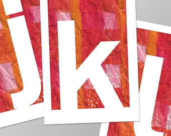 May include: Three white letters, "J", "K", and "L", cut out of paper and placed on top of a red and orange textured background.