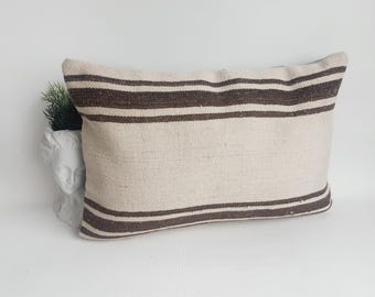 May include: A white and brown striped throw pillow with a rectangular shape. The pillow is made of a soft, woven fabric.