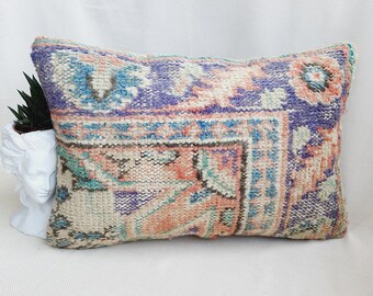 May include: A rectangular pillow with a colorful, patterned design. The pillow is made of a soft, woven fabric and features a mix of pink, blue, and white colors.