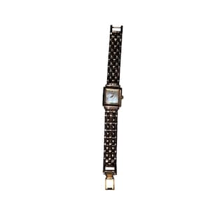 May include: A silver-toned wristwatch featuring a square face with a light-colored dial and a metallic link bracelet. The watch band consists of multiple rows of small, polished rectangular links that create a textured, chain-like appearance.