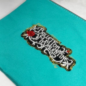 May include: A turquoise zippered pouch with an embroidered patch that says "Bullet for My Valentine" with a red rose and yellow stitching.