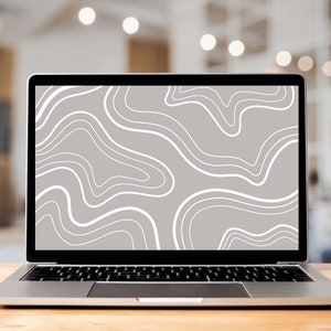 May include: A silver laptop computer with a white abstract design on the screen. The laptop is sitting on a wooden table.