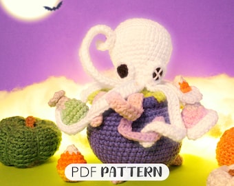 May include: Crochet amigurumi pattern for a purple cauldron with a white octopus sitting on top. The cauldron is decorated with pink, white, and green crocheted details. The pattern is available as a PDF download.
