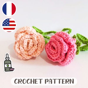 Peut inclure: Deux roses crochetées, l'une rose et l'autre pêche, avec des tiges crochetées vertes. Les roses sont sur un fond blanc avec le texte "CROCHET PATTERN" en dessous.