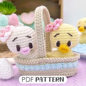 May include: A crochet pattern for a basket with two adorable crocheted chicks inside. The basket is beige with blue trim and the chicks are yellow and white with pink accents. The pattern is available as a PDF download.