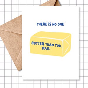May include: A white greeting card with the text "THERE IS NO ONE BUTTER THAN YOU, DAD!" in blue. The card features a yellow illustration of a butter stick. A brown envelope is partially visible.